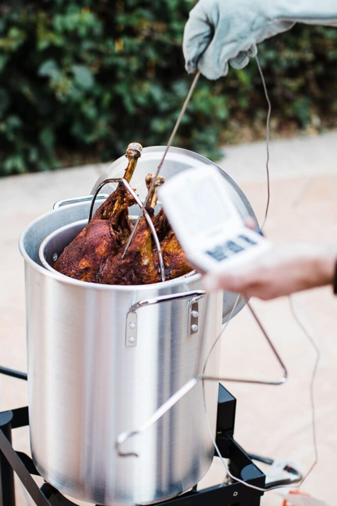 Turkey being lowered into a deep fryer outdoors