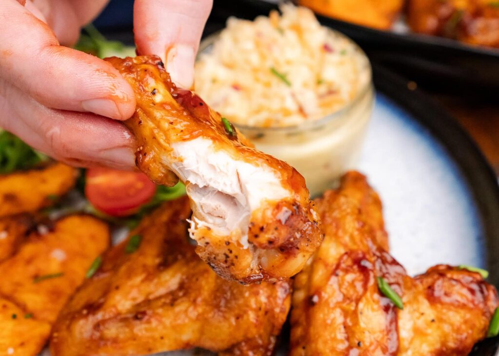 A set of air-fried wings coated in a glossy BBQ sauce, garnished with fresh parsley.