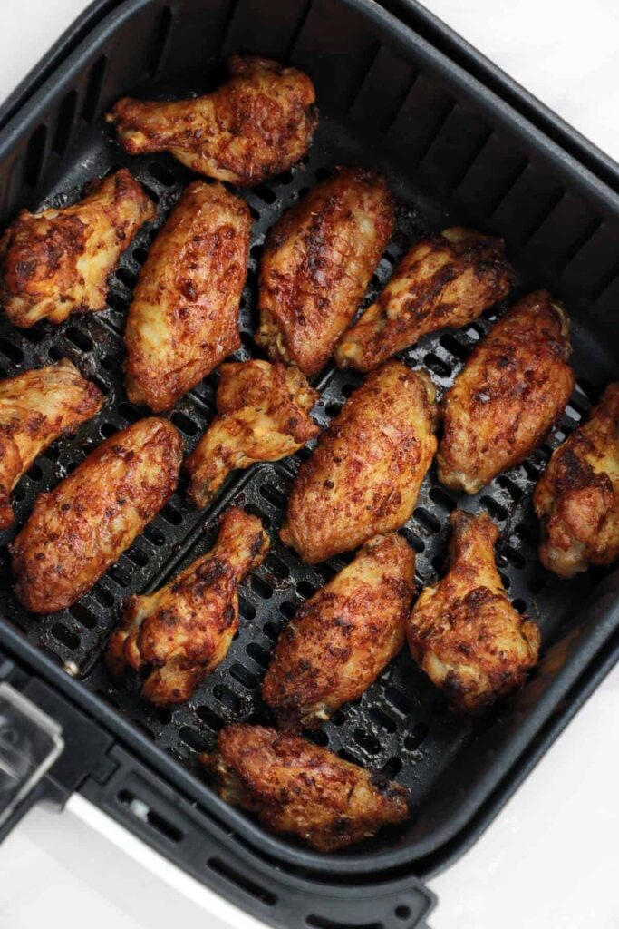 An air fryer basket filled with a single layer of chicken wings, showing proper spacing for even cooking.