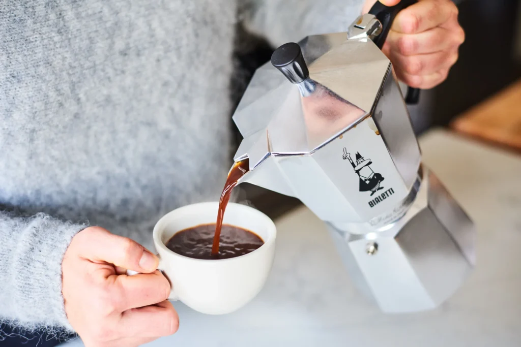  Italian Moka Pot Pouring Freshly Brewed Coffee into a Cup