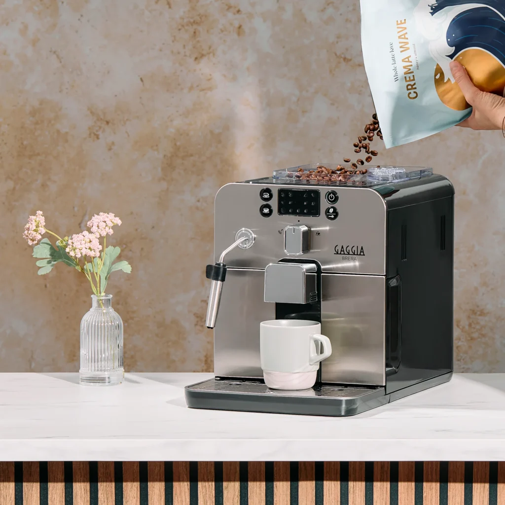 Gaggia Brera Super Automatic Espresso Machine with a compact stainless steel design, featuring a front-mounted control panel, built-in grinder, and steam wand for brewing espresso and frothing milk.