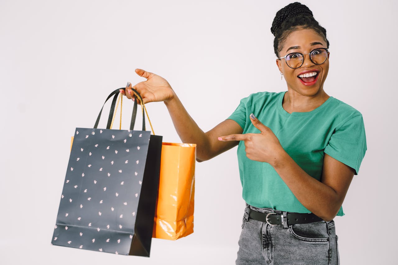 Smiling woman in a studio holding colorful shopping bags, excited about her purchases.