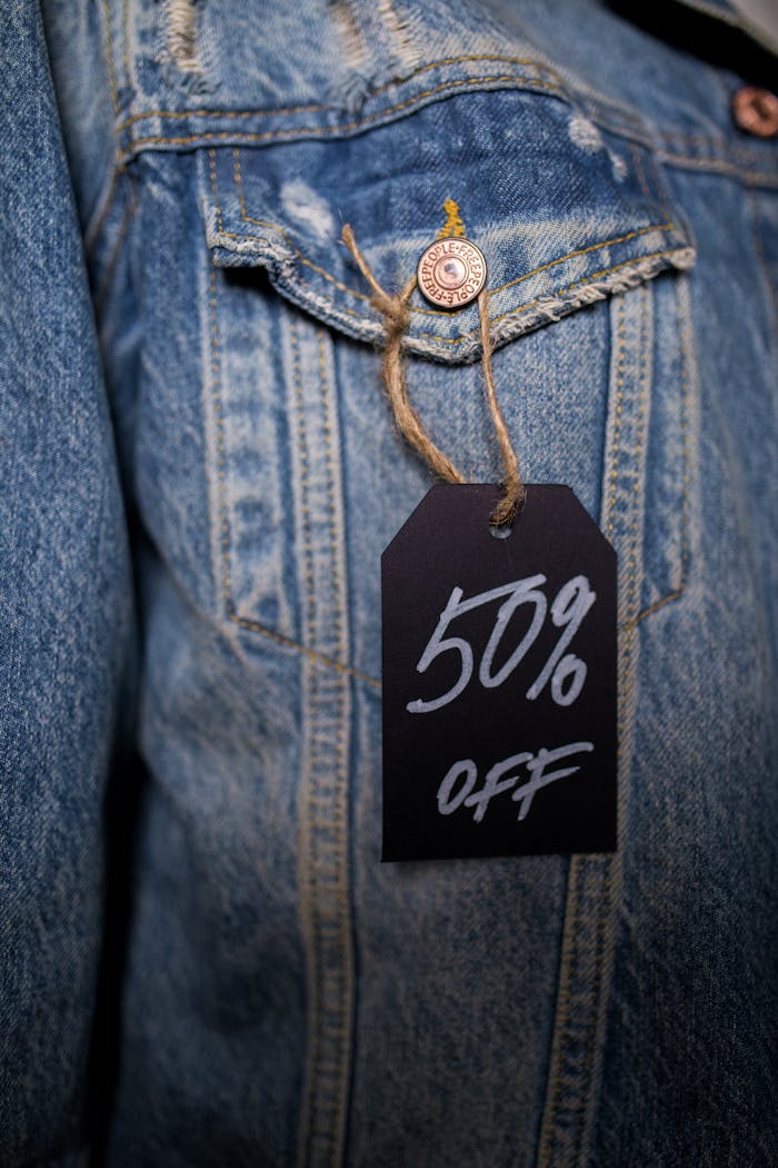 Close-up of a denim jacket with a 50% off sale tag, highlighting a discount offer.